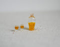 1:12 scale miniature whiskey decanter with gold stopper and 2 glasses, set of 3, filled with amber liquid, on a white surface