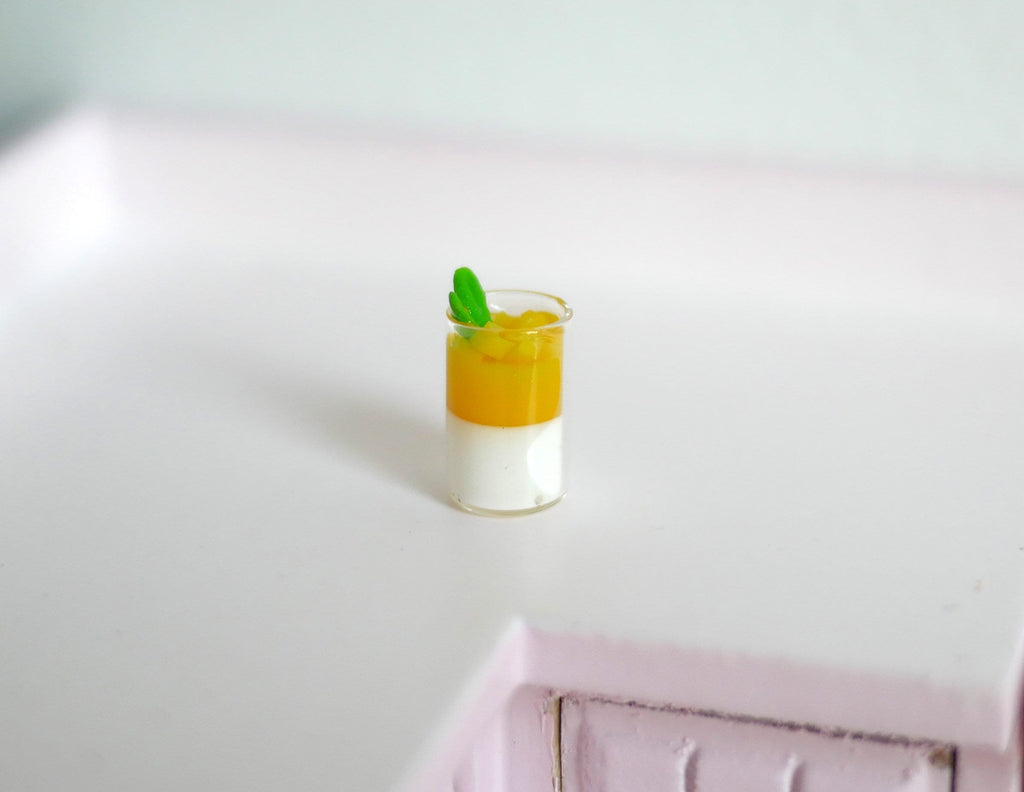 1:12 scale miniature mango summer drink in a glass with ice and lime garnish, layered orange and white, on a counter
