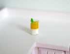 1:12 scale miniature mango summer drink in a glass with ice and lime garnish, layered orange and white, on a counter