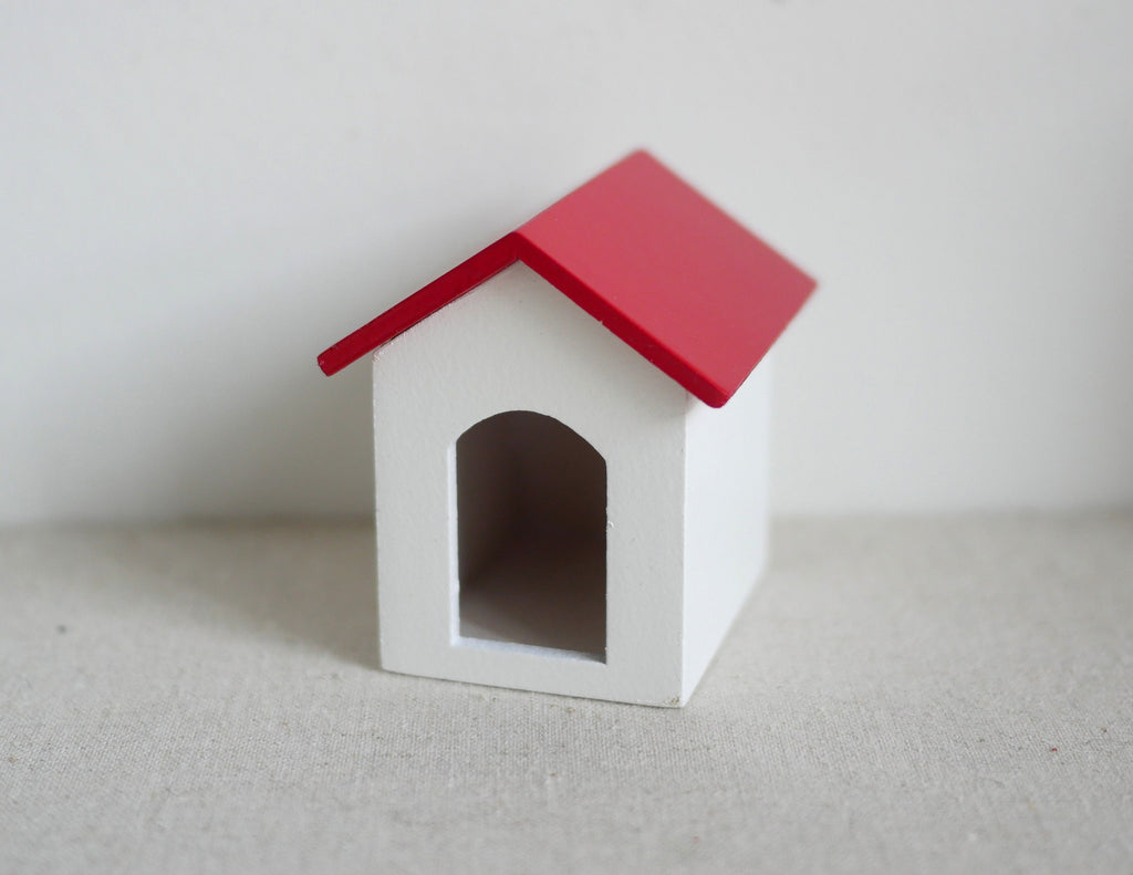 1:12 scale miniature dog house in white with red pitched roof and arched door, shown on a white surface