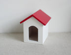 1:12 scale miniature dog house in white with red pitched roof and arched door, shown on a white surface