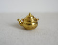 1:12 scale miniature gold metal kettle with lid and swing handle, round body, shown on a light gray surface