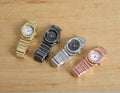 1:12 scale miniature wrist watches, set of 4, in gold, black, silver and rose gold, shown on a wood surface