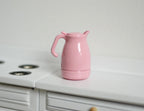 1:12 scale miniature metal kettle pitcher in pink with lid and handle, shown on a white kitchen counter