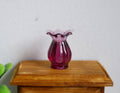 1:12 scale miniature purple vase with scalloped rim and ribbed body, translucent, shown on a wood nightstand