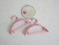 1:12 scale miniature clothes hangers in pink, set of 2, shown on a beige fabric surface beside a coin for scale