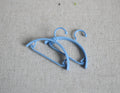 1:12 scale miniature clothes hangers in light blue, set of 2, shown lying on a beige fabric surface