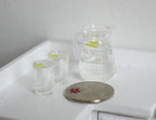 1:12 scale miniature lemon water dispenser with ice and 2 glasses, set of 3, clear, on a white counter beside a coin
