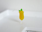 1:12 scale miniature orange summer drink with mint leaves and a straw in a stemmed glass, shown on a white counter