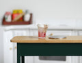 1:12 scale miniature smoothie cup in pink with a lid, shown on a kitchen table beside a coin for scale