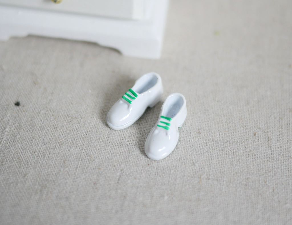1:12 scale miniature men's white sneakers with green stripes, 1 pair, shown on a beige fabric surface