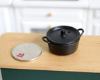 1:12 scale miniature metal cast iron look Dutch oven with lid in black, shown beside a coin for scale