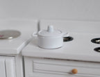 1:12 scale miniature white metal cooking pot with lid and side handles, short size, shown on a white stove