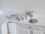 1:12 scale miniature porcelain tea set in blue floral pattern, set of 6 with jug, 4 cups and round tray, on a white counter