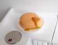 1:12 scale miniature cheesecake on a white plate with fork, one slice cut, shown on a white counter beside a coin