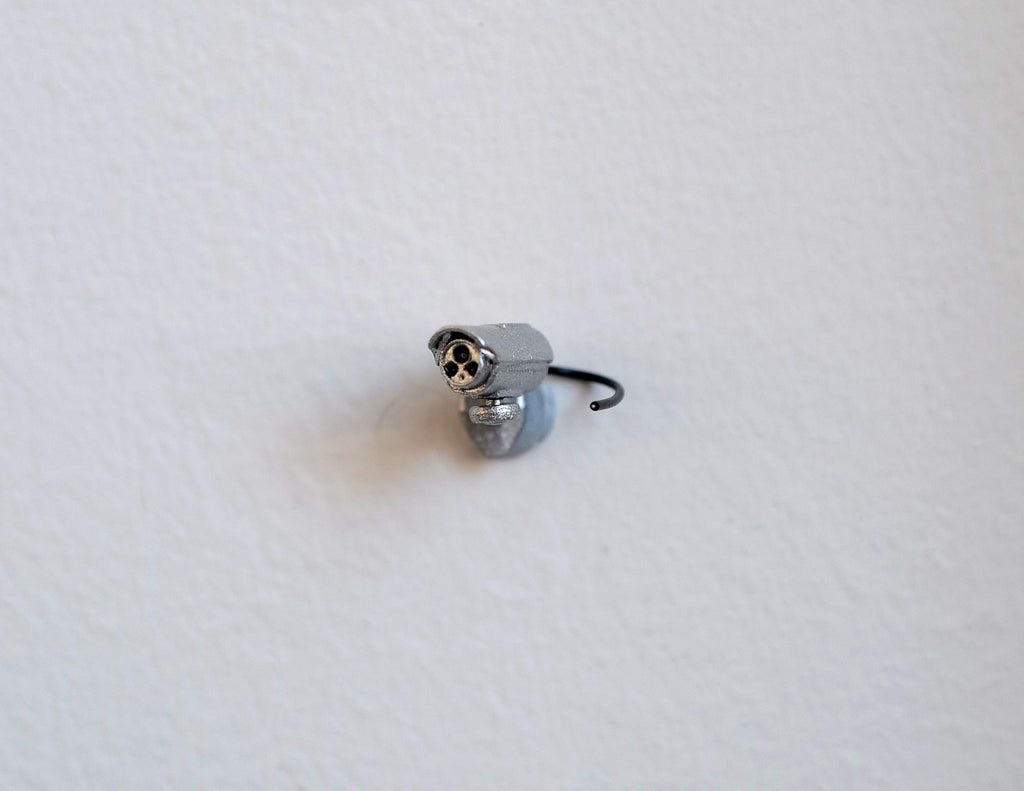 1:12 scale miniature bullet security camera in silver with a thin black antenna, shown on a white surface