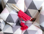1:12 scale miniature knitting needles with red yarn ball and knitted piece, shown on a gray geometric cushion