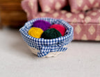 1:12 scale miniature knitting basket with blue gingham lining and yarn balls in yellow, purple, red and green