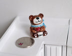 1:12 scale miniature ceramic Christmas teddy bear cookie jar, brown bear with blue scarf, beside a coin for scale