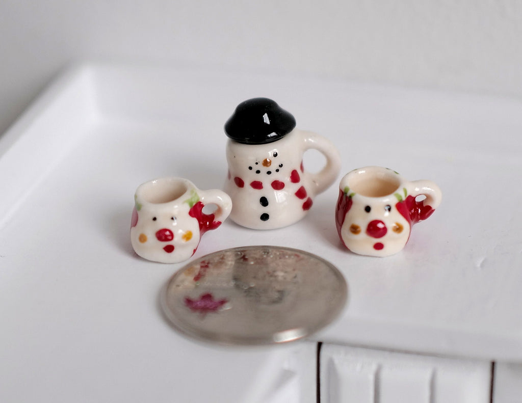 1:12 scale miniature ceramic Christmas snowman jar with black top hat lid and 2 mugs, set of 3, beside a coin