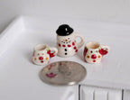 1:12 scale miniature ceramic Christmas snowman jar with black top hat lid and 2 mugs, set of 3, beside a coin