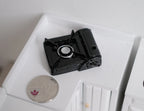 1:10 scale miniature black portable gas stove with a single burner, shown on a white counter beside a coin