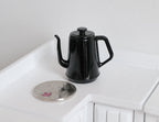 1:12 scale miniature metal gooseneck kettle in black with lid, shown beside a coin on a white counter