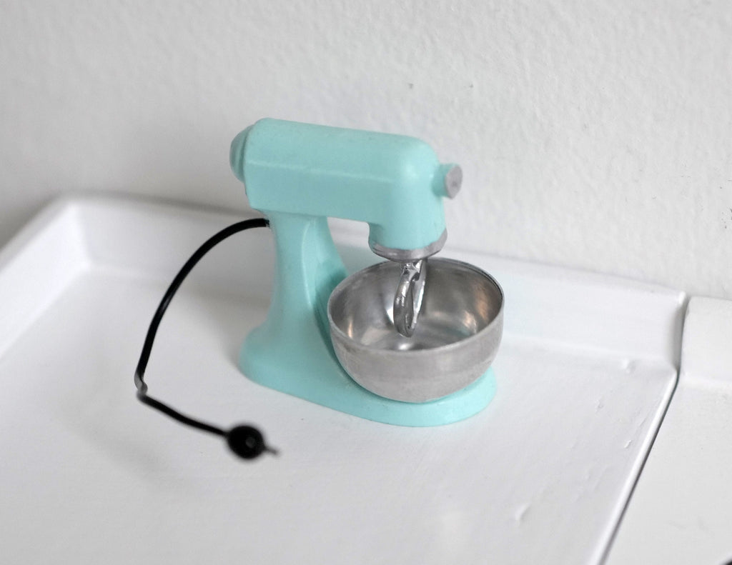 1:12 scale miniature mint green stand mixer with silver bowl and black cord, shown on a white kitchen counter