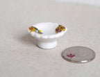 1:12 scale miniature ceramic footed serving bowl in white with yellow floral pattern, shown beside a coin for scale