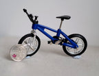 1:12 scale miniature blue kid size freestyle bike with front and rear pegs and black tires, beside a coin for scale
