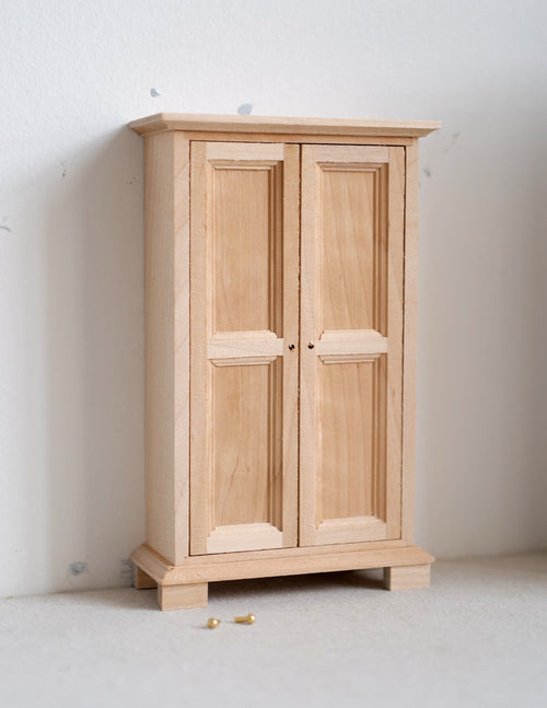 1:12 scale miniature bedroom closet armoire in bare wood with 2 paneled doors, shown closed against a white wall