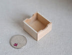 1:12 scale miniature wood storage crate in bare wood with a cutout handle, open top, shown beside a coin for scale