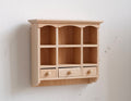 1:12 scale miniature unpainted wood kitchen wall shelf with 6 cubbies, scalloped top and three small drawers, on a white wall