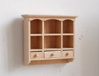 1:12 scale miniature unpainted wood kitchen wall shelf with 6 cubbies, scalloped top and three small drawers, on a white wall