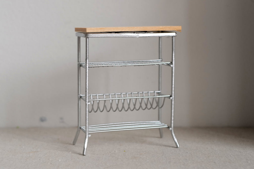 1:12 scale miniature white metal baker's rack with wood top shelf, wire shelves and a bottle rack, on a beige floor
