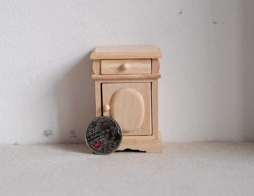 1:12 scale miniature unpainted wood nightstand with 1 drawer and arched cupboard door, shown beside a coin for scale