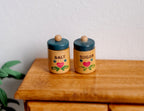 1:12 scale miniature kitchen canisters for sugar and salt with teal lids, set of 2, heart design, shown on a wood dresser