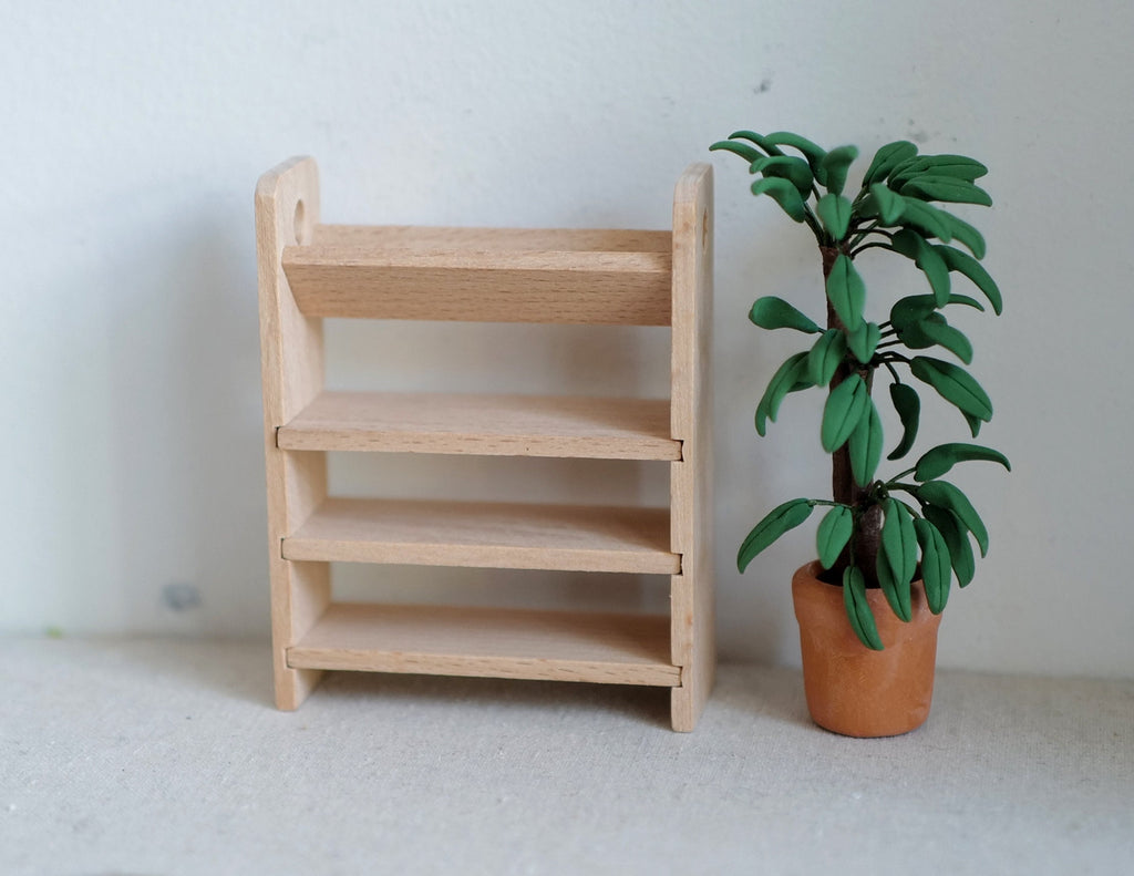 1:12 scale miniature unpainted wood shoe rack with 4 tier slanted shelves, shown beside a potted plant