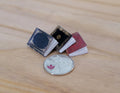 1:12 scale miniature books that open, set of 3 with blue, black and red covers, shown beside a coin for scale