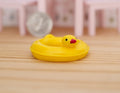 1:12 scale miniature duck pool float in yellow with orange beak, shown on a wood floor with a coin behind