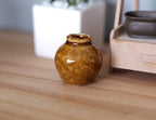1:12 scale miniature glazed ceramic planter jar in amber brown with embossed pattern, shown on a wood table