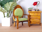 1:12 scale miniature wood armchair with oval back and light green upholstered seat, shown beside a side table and plant
