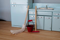 1:12 scale miniature cleaning set in red with mop, dust mop and metal bucket, set of 3, in a light blue kitchen