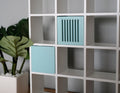 1:12 scale miniature light blue wood storage crates, set of 2 with slatted sides, shown in a white cube shelf