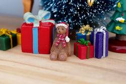 1:12 scale miniature extra small brown Christmas teddy bear with red scarf and hat, shown by gift boxes