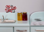 1:12 scale miniature honey and fruit jam jars with lids, set of 2, amber and dark red, on a mint kitchen counter