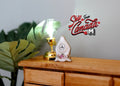 1:12 scale miniature ceramic anniversary clock in white with floral base, non working, on a wood dresser by a lamp