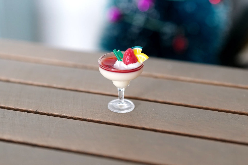 1:12 scale miniature Christmas cocktail with berries, creamy red and white drink in a stemmed glass, on a wood table