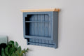 1:12 scale miniature wood kitchen wall plate rack in blue gray with slatted back and natural top, on a wall