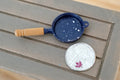 1:12 scale miniature navy blue metal frying pan with speckled enamel look and wood handle, shown beside a coin for scale